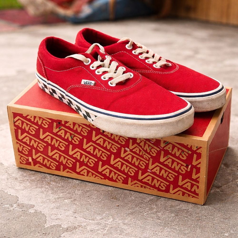 Red Vans low-top sneakers with classic checkerboard sole detail.